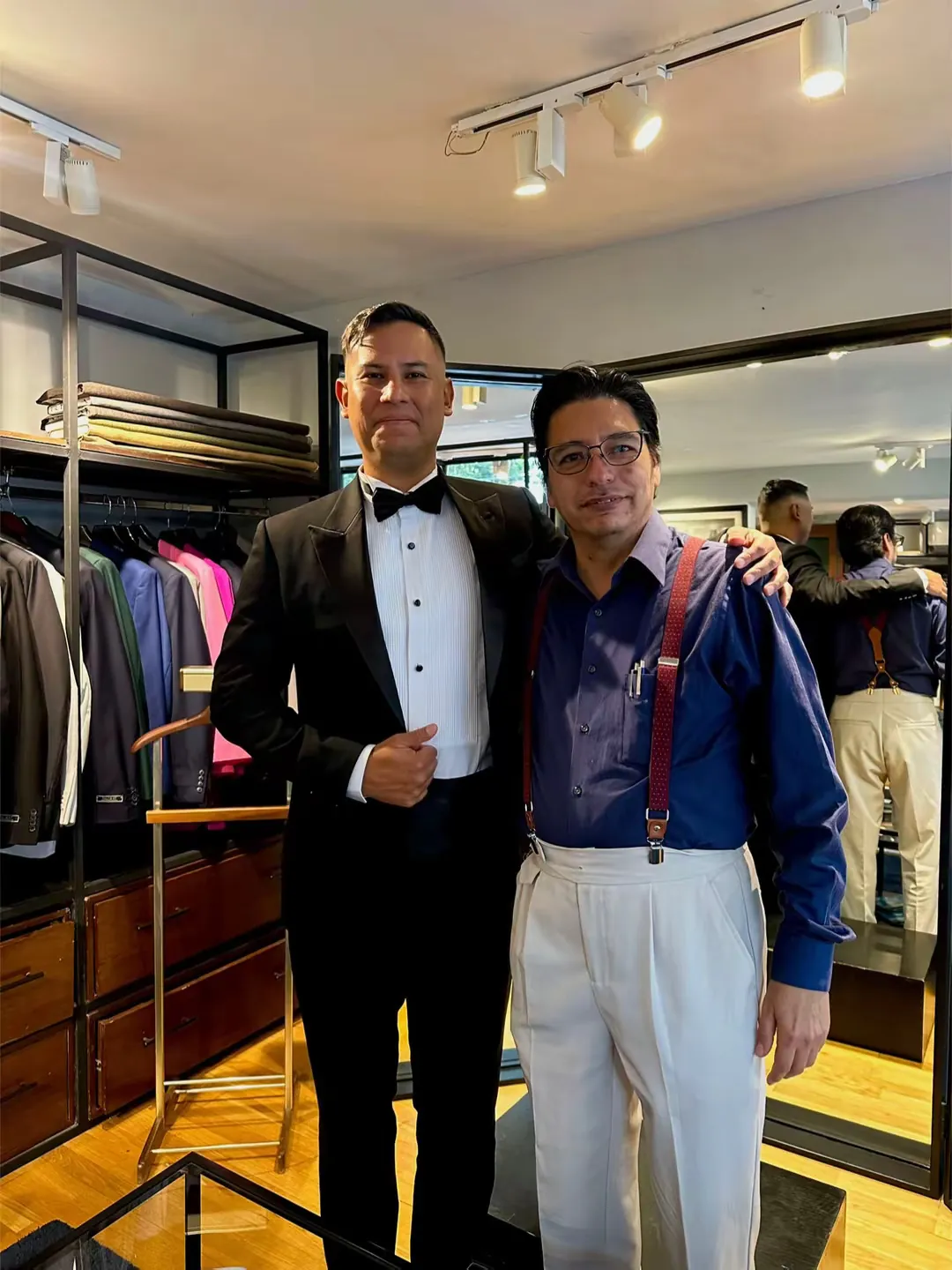Cliente en esmoquin negro junto al sastre en la sala de pruebas