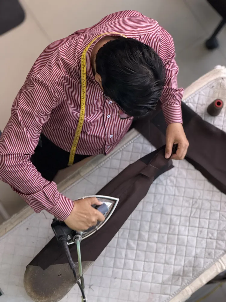 Sastrero planchando una prenda sobre la mesa de planchado