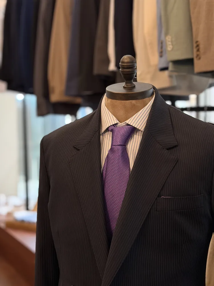 Maniquí con traje oscuro y corbata morada en la tienda VAMANA