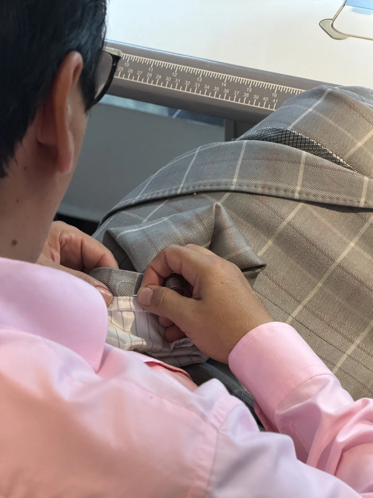 Sastre confeccionando a mano el forro de un traje a cuadros