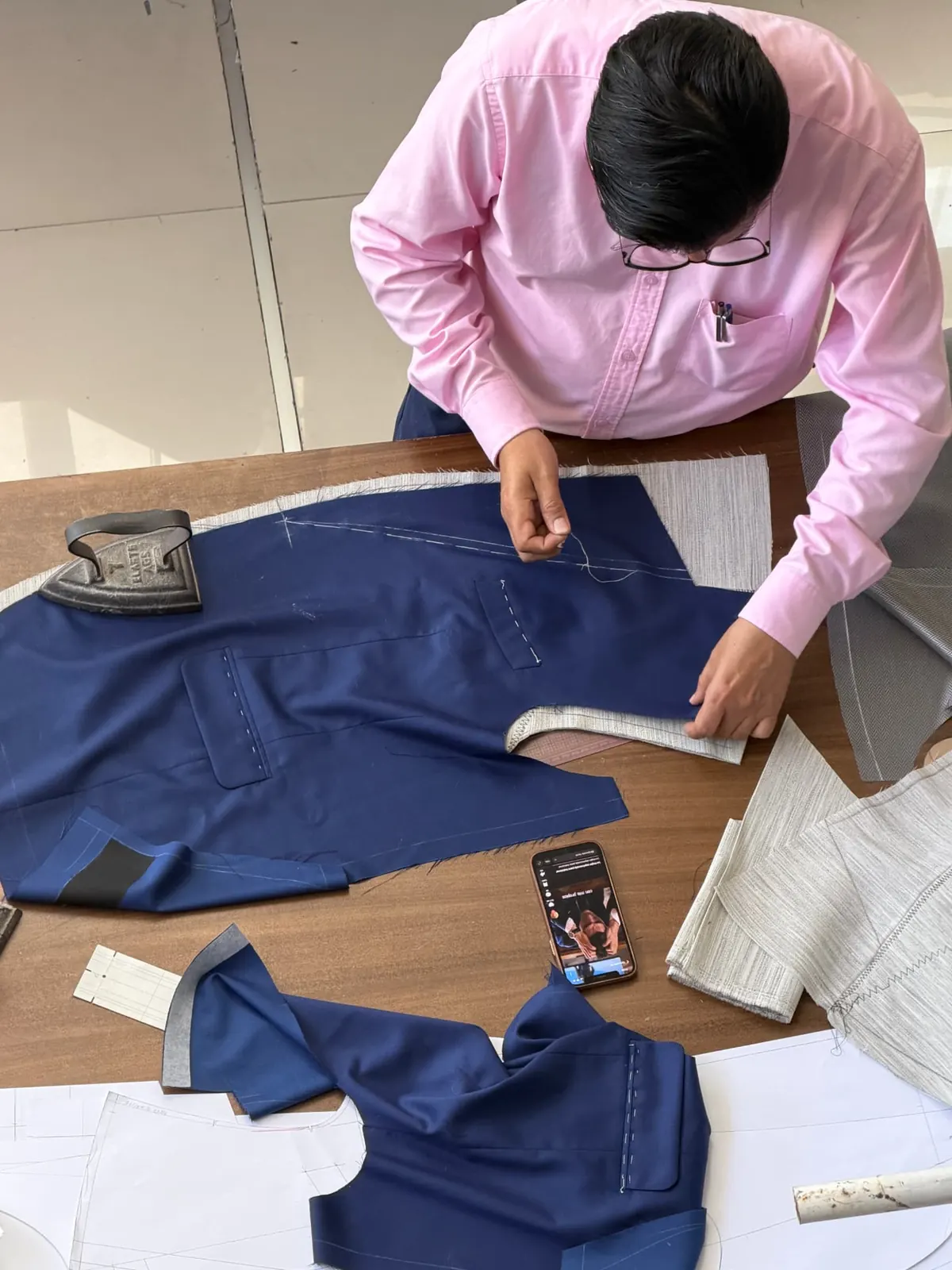 Sastre trabajando en un traje azul en el taller de VAMANA