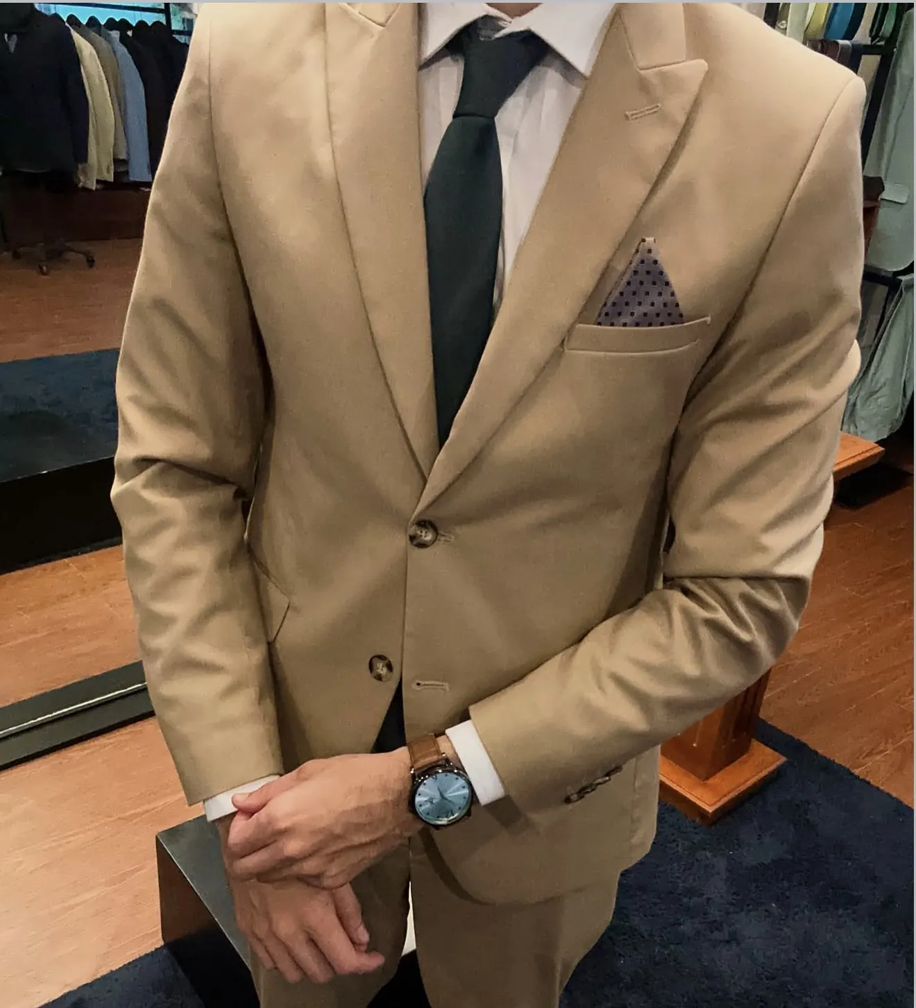Traje beige a medida con camisa blanca, corbata verde y pañuelo de bolsillo